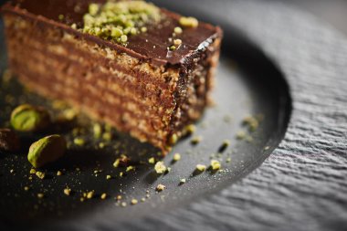 Chocolate cake with walnuts and pistachio isolated on black background. Pastry from homemade bakery