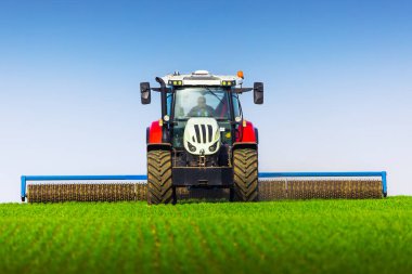 Tractor with a roller tillage on spring field. Soil rolling supports germination and is the basis for good harvesting, organic farming and agronomy clipart