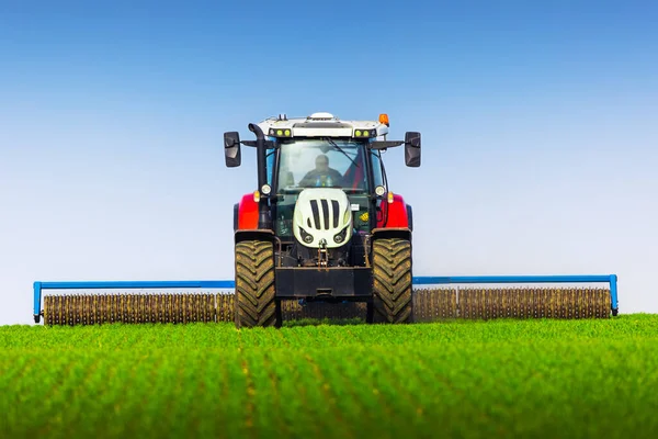 春のフィールドにローラーティレージを持つトラクター 土壌圧延は発芽をサポートし 良好な収穫 有機農業と農業の基盤です — ストック写真