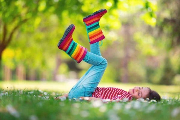 可爱的小女孩 穿着雨衣 脚踩着雨靴 在外面的绿地里嬉戏 花园里开着盛开的菊花 孩子们的画像 — 图库照片
