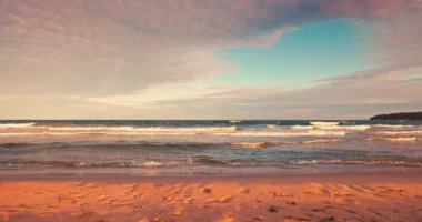 Sahilde ve kumlu sahilde dalgaların üzerinden tropik deniz doğuşu, 4K yavaş çekim videosu