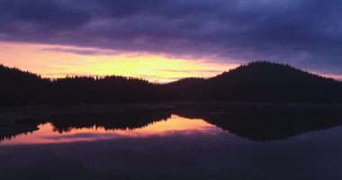 Göl suyunun ve yeşil orman çam ağaçlarının üzerinde renkli bir gündoğumu. Baraj Shiroka polyana (Geniş çayır) Rodopi dağlı doğa manzarası. Bulgaristan