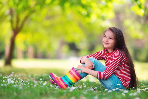 かわいいです幼児女の子で雨ゴムブーツ遊び外で緑の公園で咲きフィールドのデイジーの花 子供の肖像画 — ストック写真