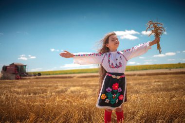 Hasat zamanı tarım buğday tarlasında geleneksel Bulgar folklor kostümlü genç kız sanayi makinesiyle birleştirildi