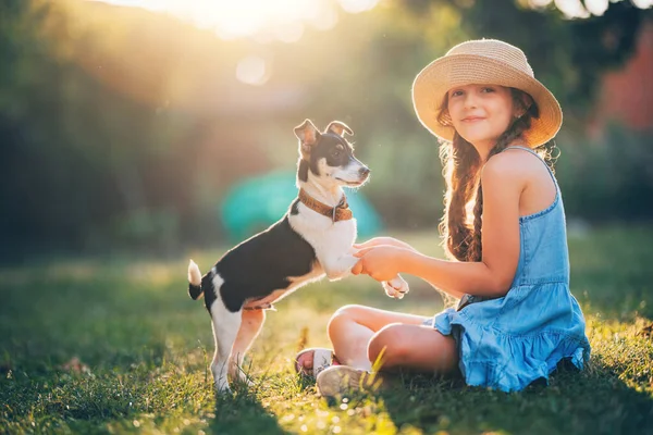 Parkta güneşli bir günde sevimli yavru köpekle oynayan mutlu kız.