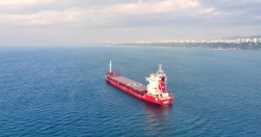 Kargo gemisi, sisli deniz doğumu, deniz manzarası ve şehir manzarası boyunca sanayi limanına doğru yol alıyor.