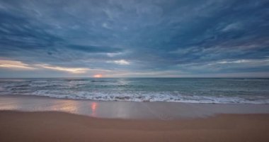 Bulutlu, tropik plajlı dramatik gündoğumu ve su sıçratan deniz dalgaları videosu