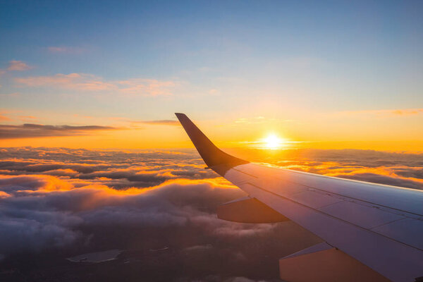 Airplane flight in sunset sky over ocean water and wing of plane. View from the window of the Aircraft. Traveling in air.