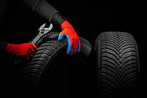 Winter car tires service and thumbs up hands of mechanic with wrench, screwdriver on black background