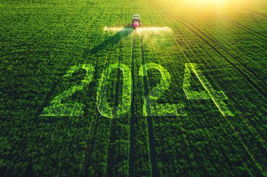 2024 Mutlu Yıllar konsepti ve tarla sürme ve püskürtme çiftçilik traktörü görüntüsü.