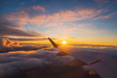 Gün batımında okyanus suyu ve uçağın kanadı üzerinde uçak yolculuğu. Uçak 'ın penceresinden bak. Havada yolculuk..