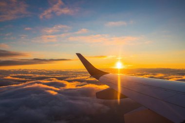 Gün batımında okyanus suyu ve uçağın kanadı üzerinde uçak yolculuğu. Uçak 'ın penceresinden bak. Havada yolculuk..
