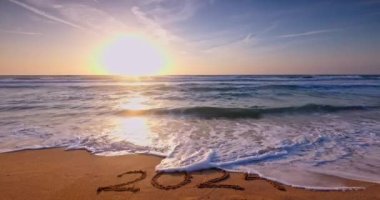 Metin 2024 Tropikal adanın deniz kumları üzerine yazılmış ve güzel bir sabah güneşi 4k video.