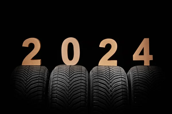 Car tires, winter wheels and text new year 2024 isolated on black background