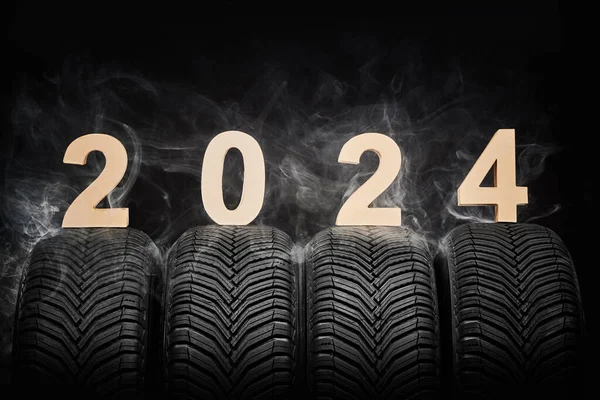 Car tires, winter wheels, isolated new tyres, fog and happy new year 2024 black background .