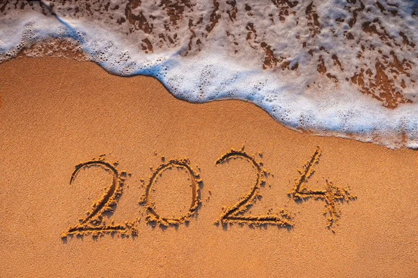 ハッピーニューイヤー2024コンセプト ビーチでレタリング 日の出に海浜に書かれたテキスト ストック画像