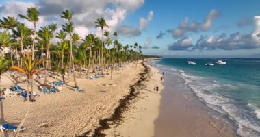 Tropik plaj, Karayip denizi ve kumlu sahilde yürüyen insanlar Punta Cana, Dominik Cumhuriyeti üzerinde gün doğumunu karşılıyor.