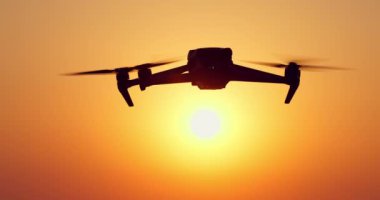 Deniz ufkundan yükselen güneş, su üzerinde güneş ışığına doğru uçan dron.