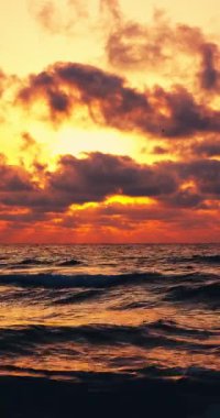 Sakin deniz dalgaları üzerinde tropikal renk bulutları ve bulutlar arasında güneş ışınları dikey panorama 4k video