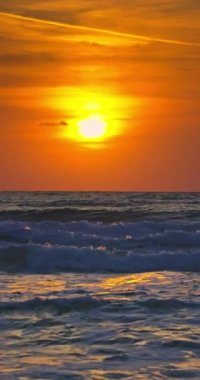 Deniz dalgalarının üzerinde gün doğumu, okyanus ufkunun üzerinde yükselen güneş dikey video