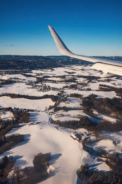 雪山の上を低く飛行し 空港に着陸するための準備 翼タービンとスカイラインの飛行機窓からの眺め ロイヤリティフリーのストック写真