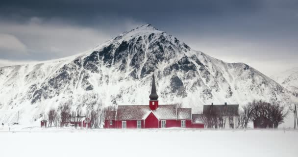 スカンジナビアのパノラマの自然景観 風光明媚な山のピークと古い赤い教会 フラクスタッド ロフテ島 ノルウェー 冬の雪のビデオ中に — ストック動画