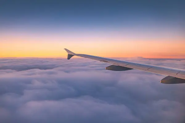 飞机在日落或日出时飞越彩云 从机翼涡轮机和地平线的平面窗口看风景 免版税图库照片