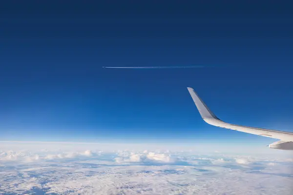 風光明媚な夕日や日の出雲の間にカラースカイ雲の上を飛行する飛行機 翼タービンと地平線の飛行機窓からの眺め ストックフォト