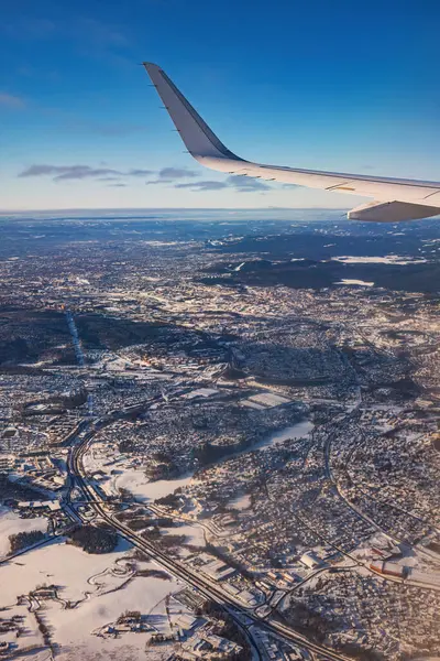 飞机低空飞行在多雪的高山上 准备降落到机场 从机翼涡轮机和天窗的平面上俯瞰 免版税图库图片