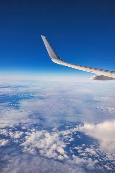飞机在日落或日出时飞越彩云 从机翼涡轮机和地平线的平面窗口看风景 图库照片