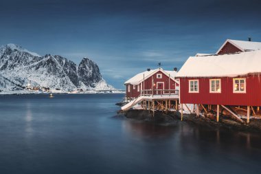 Lofoten Adaları, Reine, Norveç ve Hamnoy balıkçı köyleri. Kış mevsiminde kırmızı ışıklı evleri olan doğa manzarası.