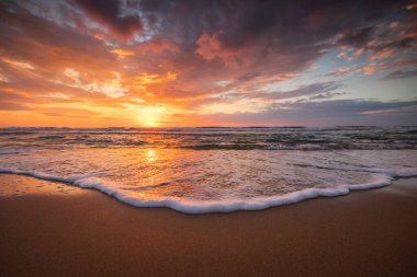 Sahilde renkli bulutlarla okyanusun doğuşu.