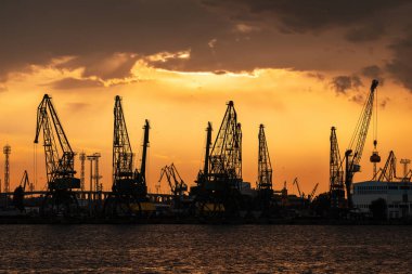 Bulgaristan 'ın Varna limanı ve sanayi vinçleri gün batımından önce çalışıyor