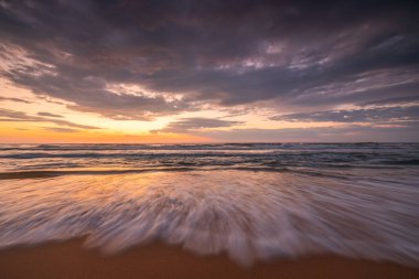 Denizin üzerinde dramatik bulutlar, güneşin doğuşu.