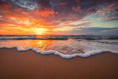 Sahildeki dalgalara yakın ve denizin üzerinde güzel bir gün doğumu