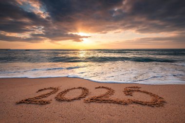 Tropikal kumsalda, deniz doğumu manzarasında mutlu yıllar 2025 konsepti. 