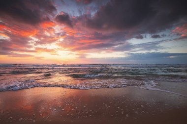 Tropikal ada sahili üzerinde dramatik bulutlarla birlikte renkli okyanus gündoğumu