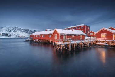 Lofoten Adaları, Reine, Norveç ve Hamnoy balıkçı köyleri. Kış mevsiminde kırmızı ışıklı evleri olan doğa manzarası.