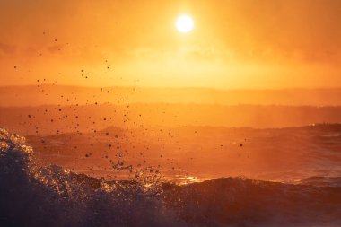 Su Sıçratan ve Puslu Okyanus Dalgaları Altında Altın Gün Batımı