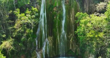 Dağlık tropik yağmur ormanlarının kalbinde çağlayan şelale manzarası ve parlayan güneş ışığı