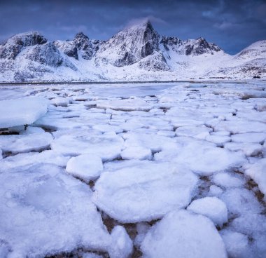 Donmuş sahil kayalarından oluşan dikey kış denizi manzarası, fiyortlar dağ zirveleri Lofoten adaları, Norveç