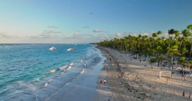 Palmiye ağaçları ve Mavi Karayip kıyı dalgalarıyla tropik plaj güneşli bir gökyüzü manzarası altında Bavaro, Punta Cana, Dominik Cumhuriyeti