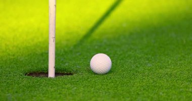 Golf sahasında yeşil çimenler, bayrak direği, delik, güneşli bir günde golf topu. Tropik ada Dominik Cumhuriyeti 'nde golf