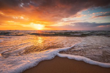 Sahildeki dalgalara yakın ve kumların ve dalgaların üzerinde güzel bir gün doğumu