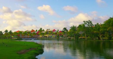 Güneşin doğuşu sırasında golf sahasında palmiye ağaçları ve göl manzarası