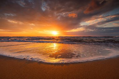 Sahne bulutlu okyanus gündoğumu ve deniz kumlarında dalgalanan güzel yaz plajı. 