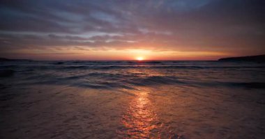 Deniz dalgaları ve sahil kıyısında güzel dramatik bir gün doğumu.