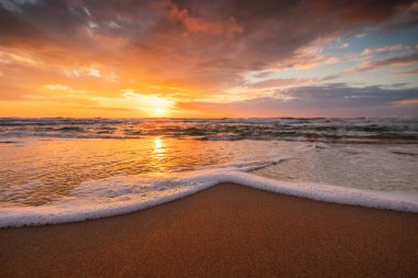 Deniz dalgaları ve sahil kıyıları üzerinde güzel bulutlu gün doğumu