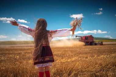 Hasat zamanı tarım buğday tarlasında geleneksel Bulgar folklor kostümlü genç kız sanayi makinesiyle birleştirildi