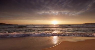 Sakin okyanus sahili üzerinde gün doğumu kumda altın güneş ışığı, manzaralı bulutlu tropikal deniz gündoğumu.